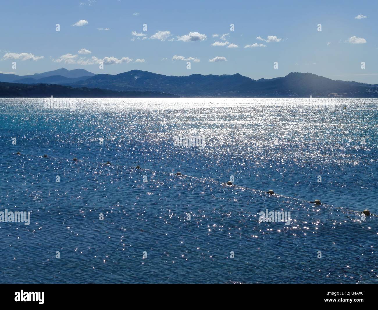 Un blu nuvole, il cielo riflesso nel mare e groynes in primo piano. Romantica atmosfera luminosa sul mare Foto Stock