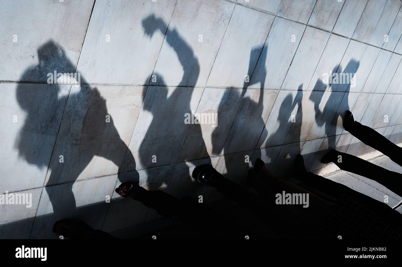Non saprai mai chi dietro a tutto questo duro lavoro. Ombre di persone che utilizzano vari dispositivi. Foto Stock