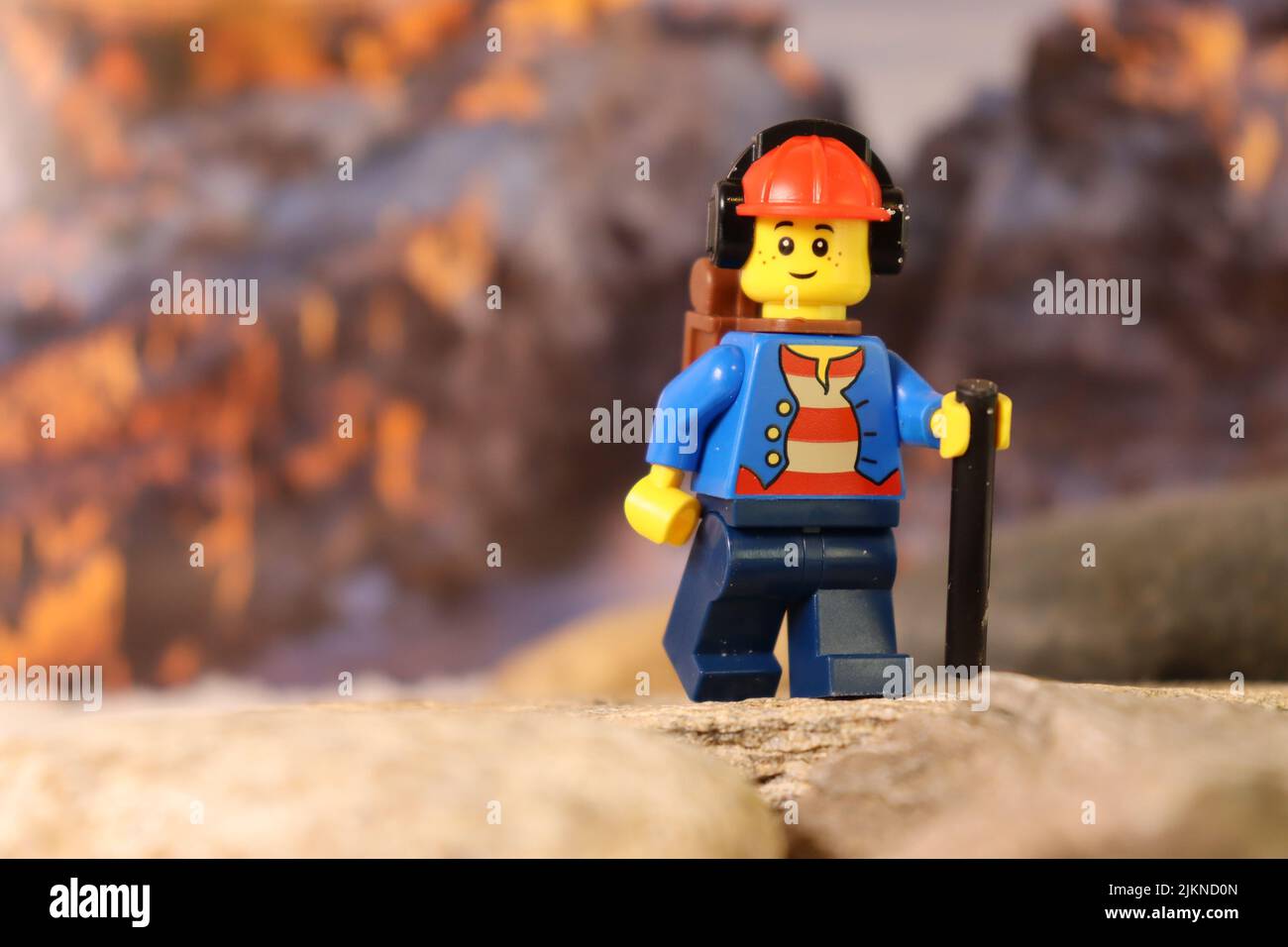 Il personaggio giocattolo Lego di un escursionista con un bastone sullo sfondo delle montagne Foto Stock