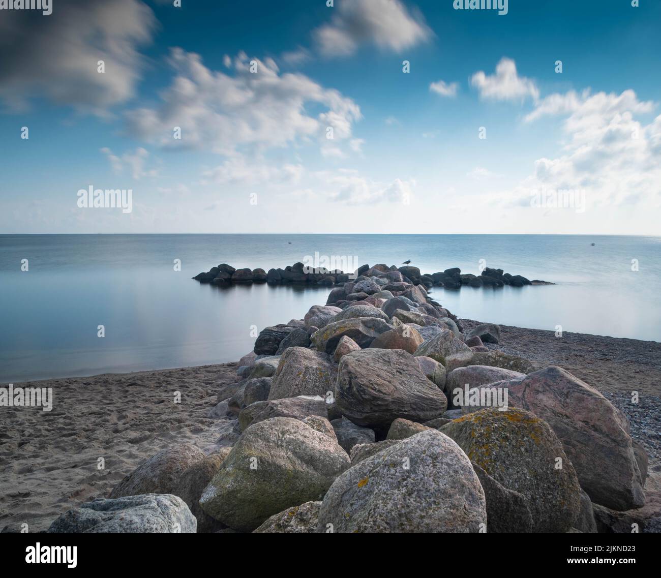 Una selezione di pietre di un frangiflutti in una mattinata di sole Foto Stock