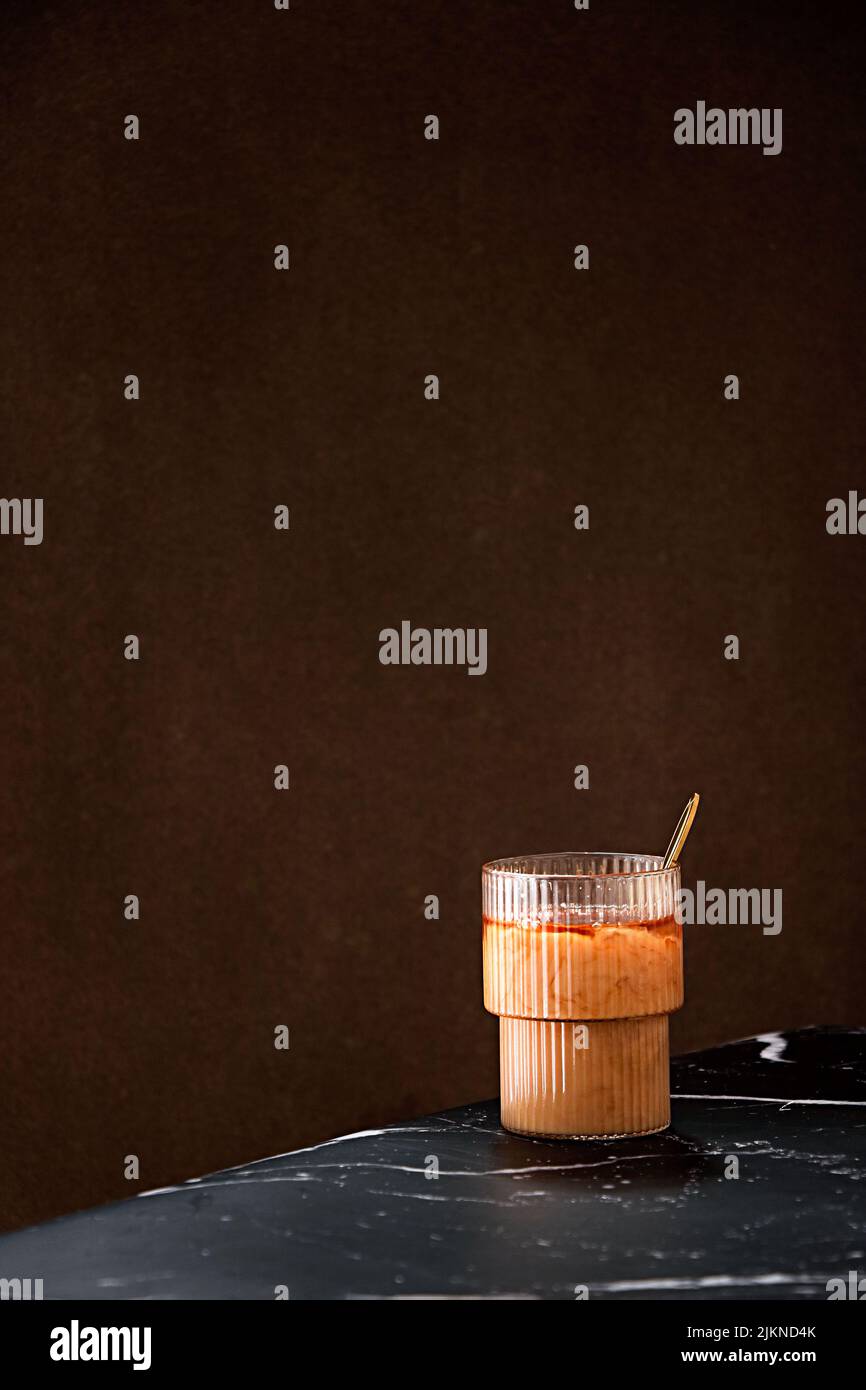 Uno shot verticale di una tazza di caffè ghiacciato sul piano portapaziente nero Foto Stock