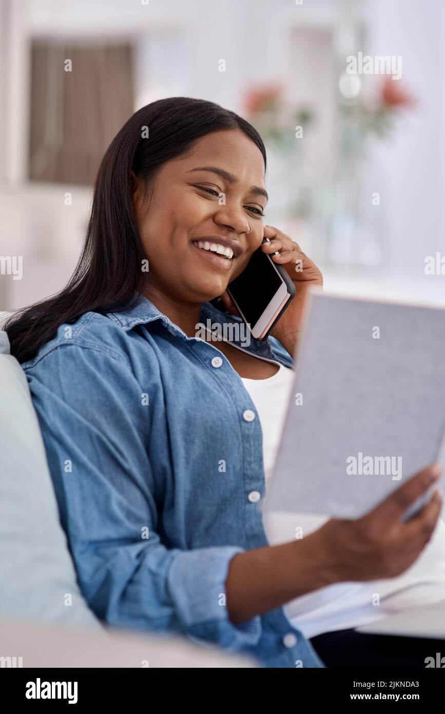 Im che chiama per invitarti a scansionare il mio bambino la settimana prossima. Una donna che guarda il suo notebook mentre parla sul suo cellulare a casa. Foto Stock