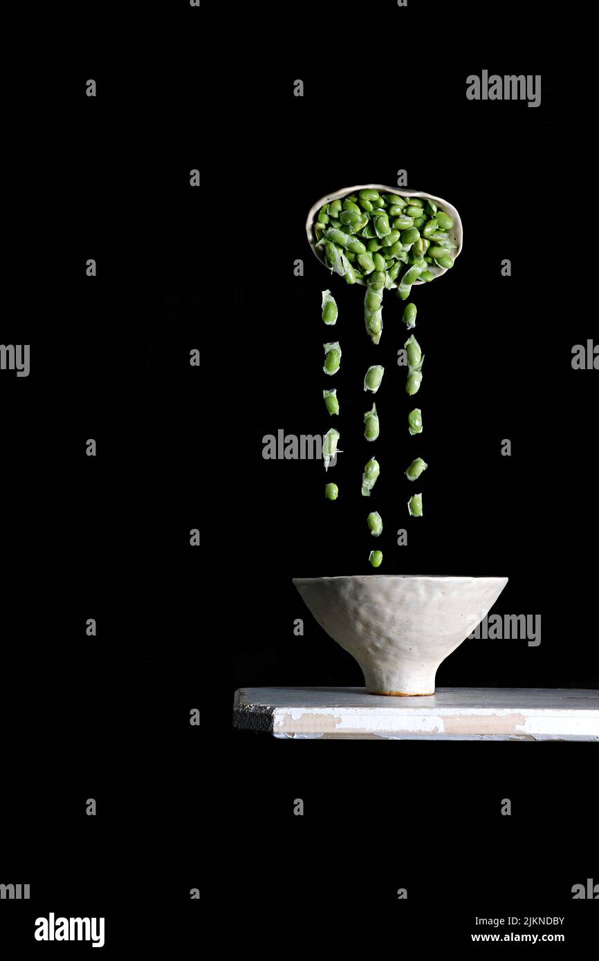 Un colpo verticale di soia che spruzzi e galleggia nell'aria isolato su uno sfondo nero Foto Stock
