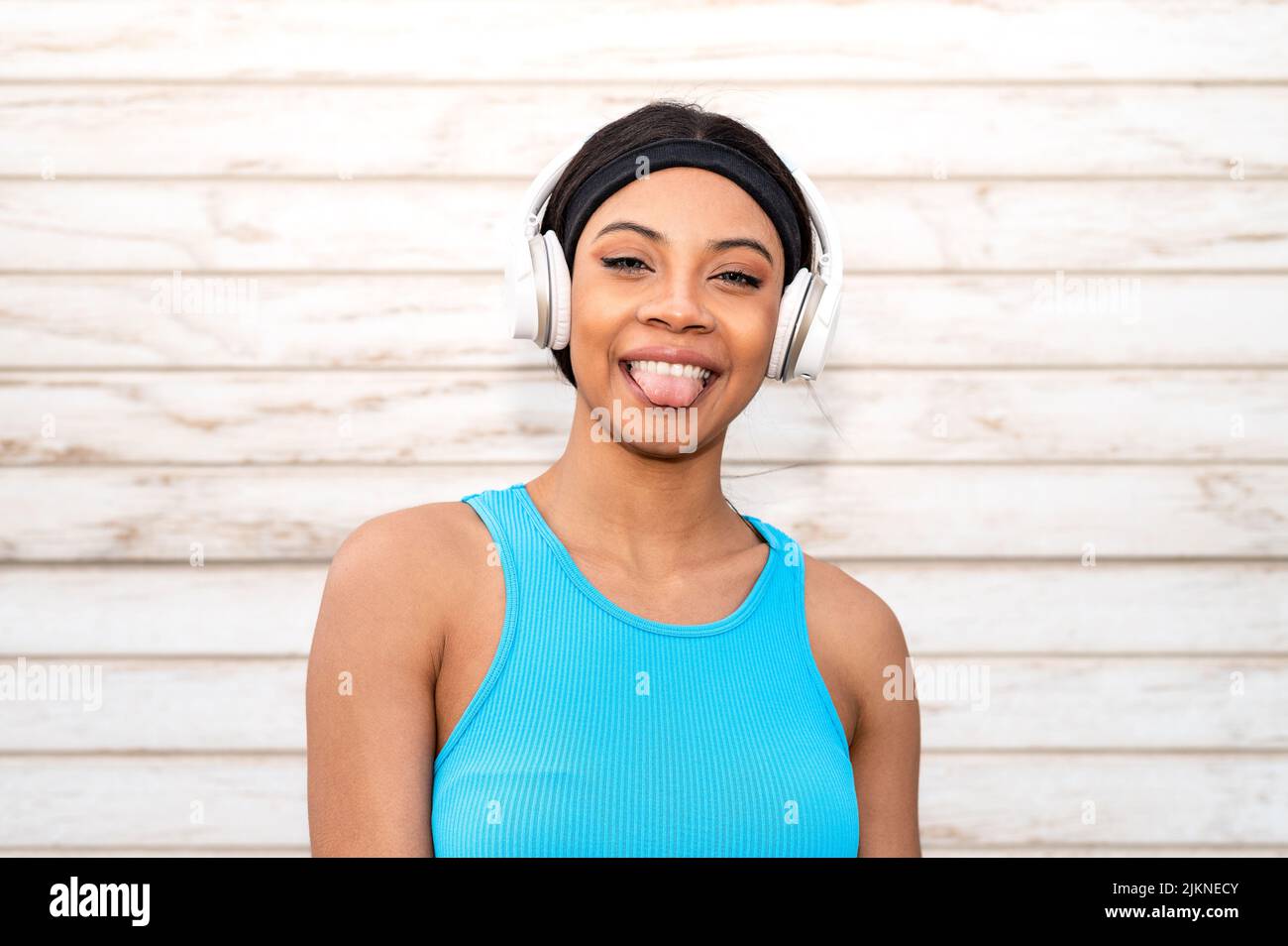 Ritratto di una allegra donna afroamericana che indossa abbigliamento sportivo e cuffie. Foto Stock