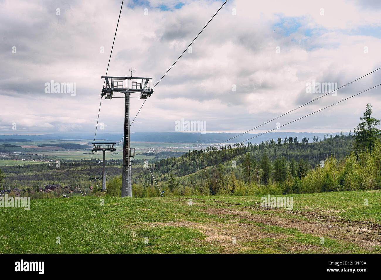 Un colpo verticale di skilift su campo e foresta sotto un cielo nuvoloso durante il giorno Foto Stock