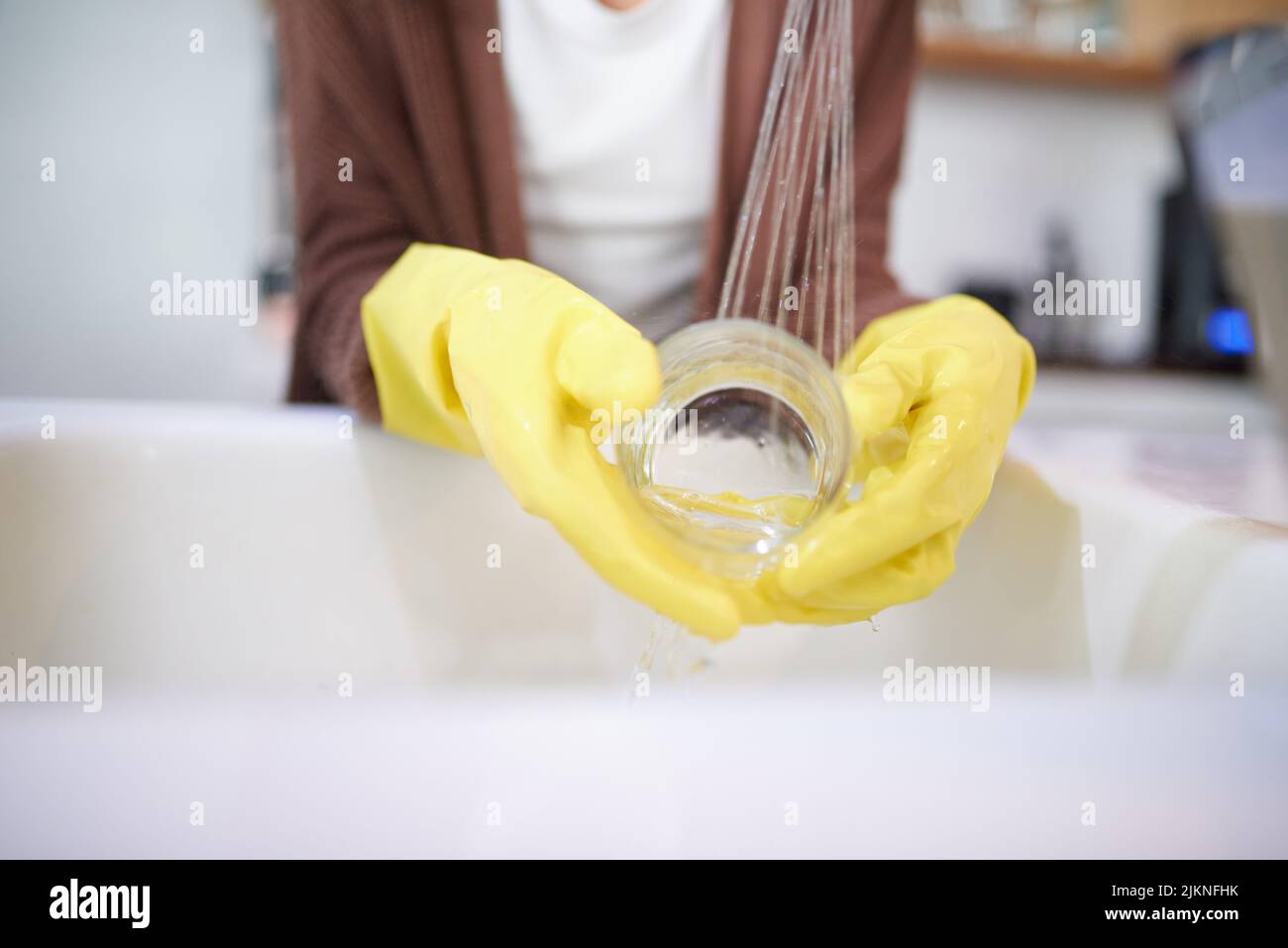 Non basta lavare, sciacquare, una donna irriconoscibile che lava i piatti a casa. Foto Stock