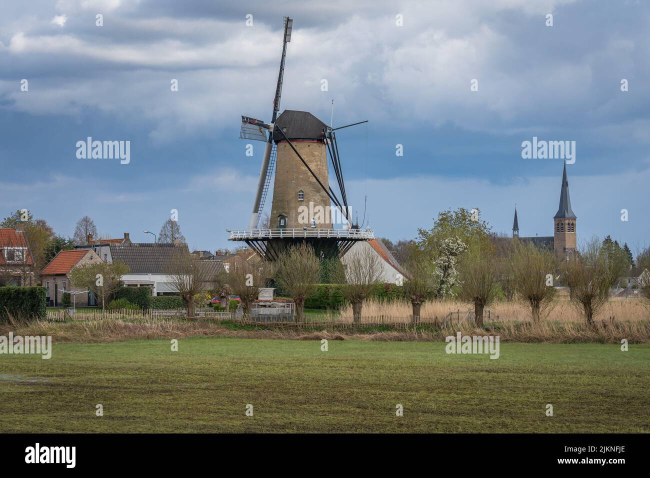 Campagna olandese con mulino a vento tradizionale vicino alla chiesa nel villaggio di Terheijden, Brabante Nord Foto Stock