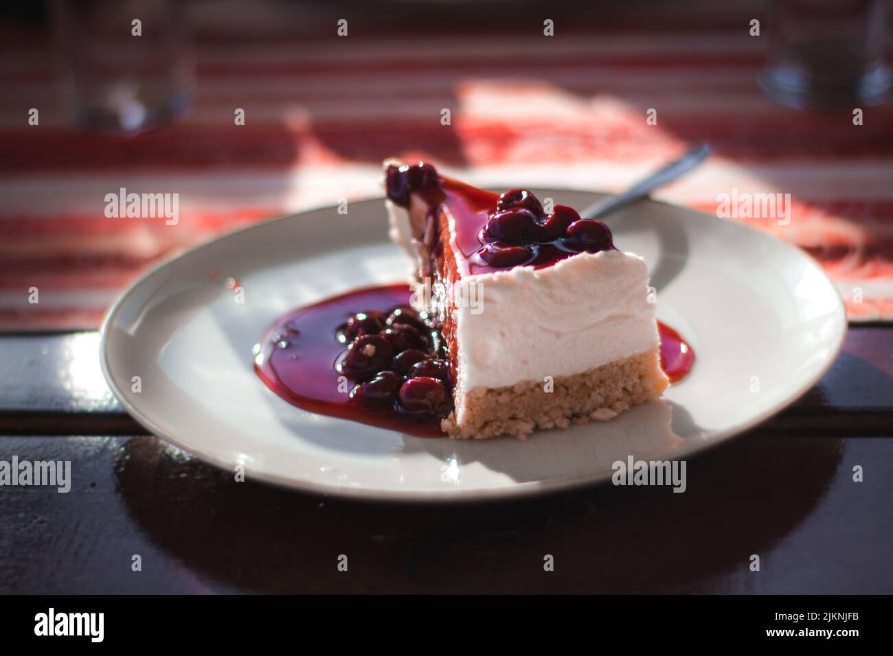 Un primo piano di una fetta di torta di lamponi in piatto bianco con fondo sfocato Foto Stock