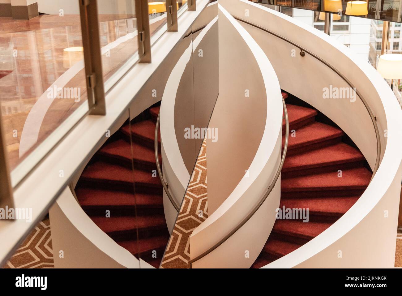 Una scala rossa a spirale vicino a uno specchio riflettente Foto Stock