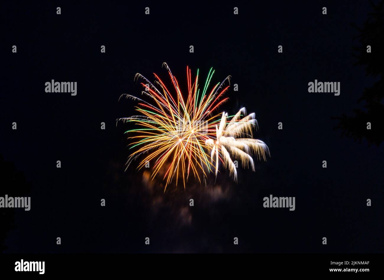 Una vista di colorati fuochi d'artificio nel cielo notturno scintillante e che crea un'atmosfera festosa Foto Stock