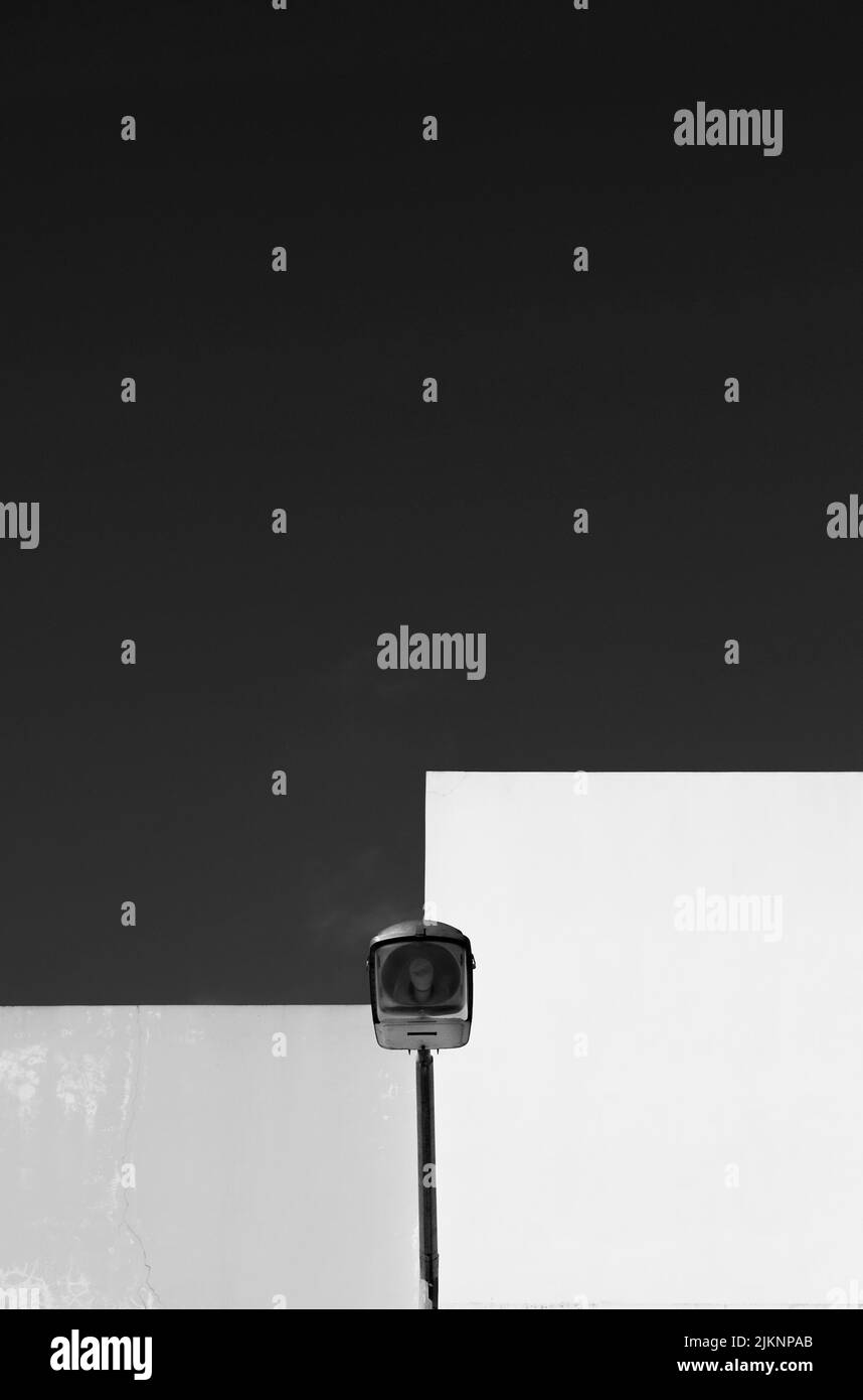 Immagine verticale in scala di grigi di una lampada da strada e di una parete bianca Foto Stock