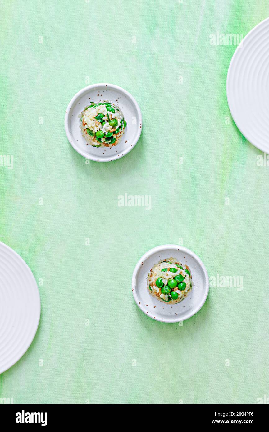 Una vista verticale dall'alto di due piatti con riso e verdure su sfondo estetico verde chiaro Foto Stock