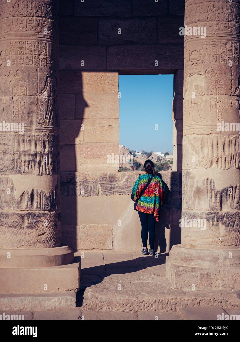 Una femmina che guarda da una finestra su un antico edificio Egiziano Foto Stock