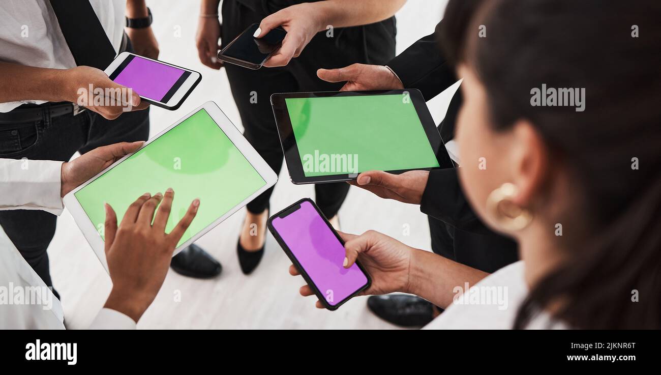 La tecnologia ci tiene aggiornati con tutto. Primo piano di un gruppo di imprenditori irriconoscibili che utilizzano dispositivi digitali in ufficio. Foto Stock
