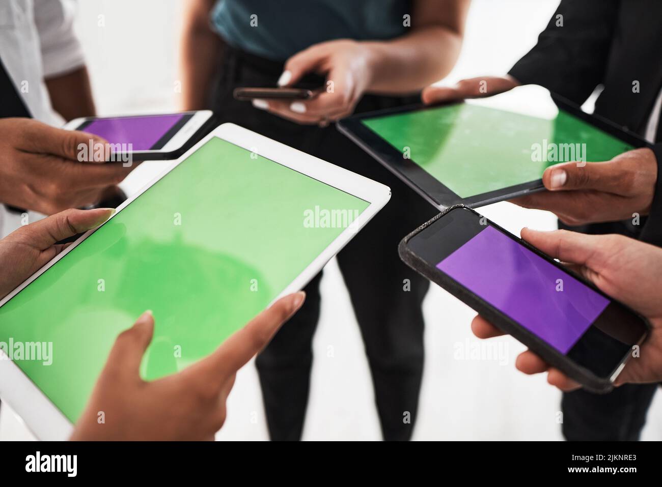 Connettiti e condividi in un istante. Primo piano di un gruppo di imprenditori irriconoscibili che utilizzano dispositivi digitali in ufficio. Foto Stock
