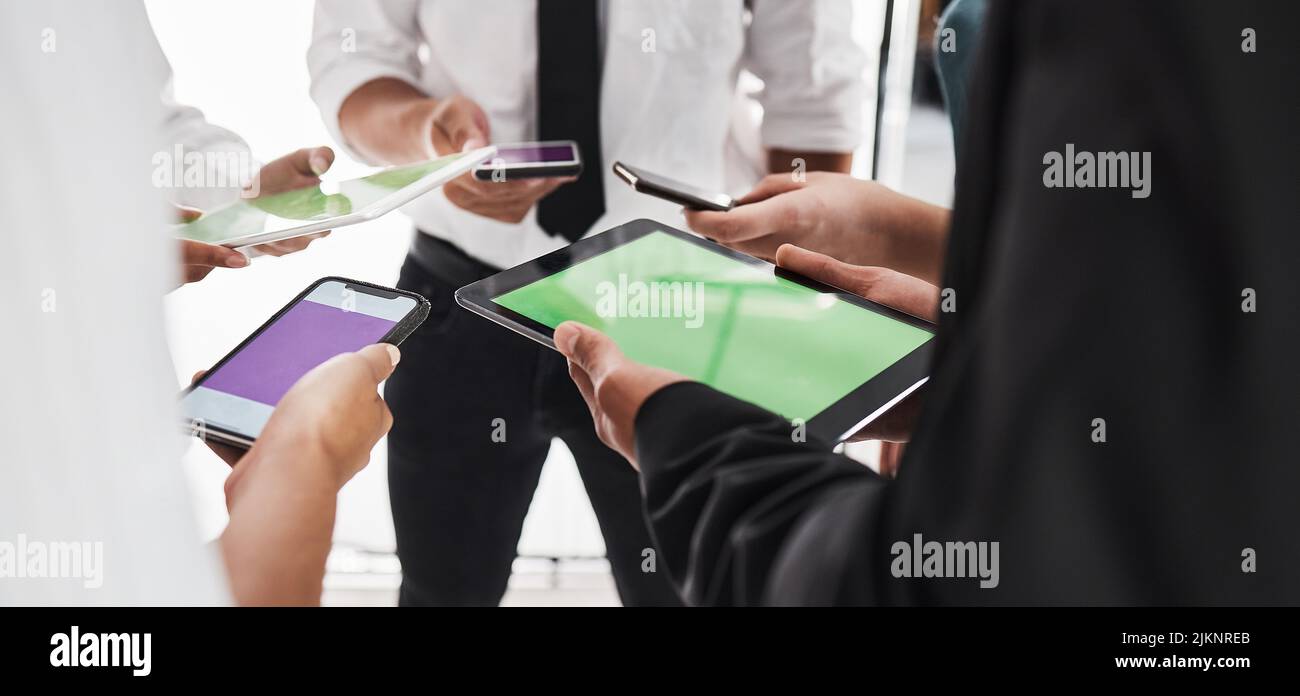 Collegamento fino a ottenere più fatto. Primo piano di un gruppo di imprenditori irriconoscibili che utilizzano dispositivi digitali in ufficio. Foto Stock