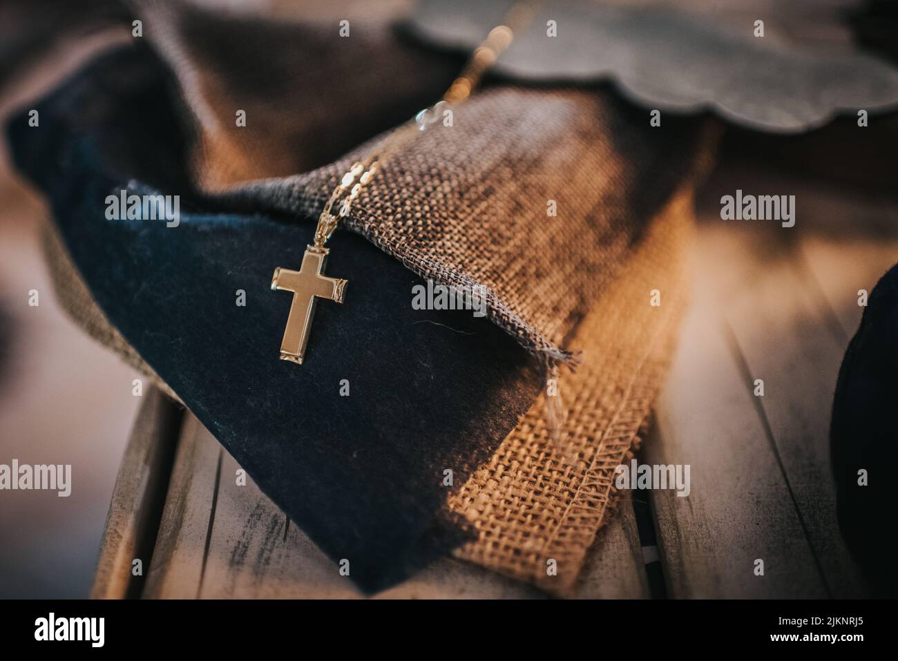 La croce dorata con catena su un pezzo di tessuto su un tavolo di legno Foto Stock