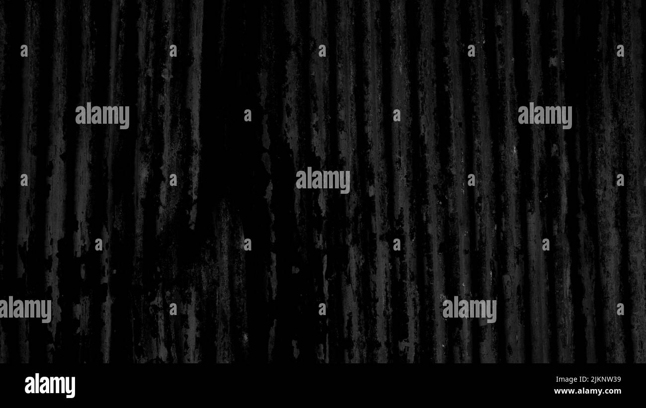 Un primo piano di una vecchia superficie metallica testurizzata nera con linee verticali. Foto Stock