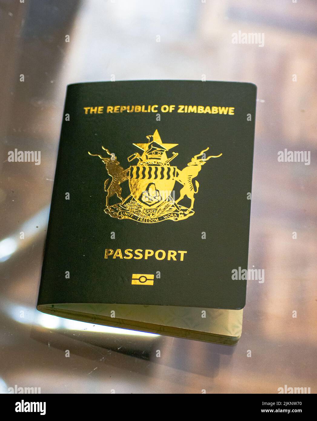 Un primo piano del passaporto della Repubblica dello Zimbabwe su un tavolo trasparente Foto Stock