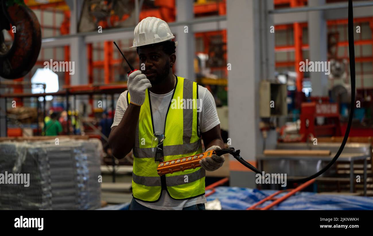 African american Foreman or Worker Control Crane industriali fornitori per il caricamento in fabbrica linea di produzione Foto Stock