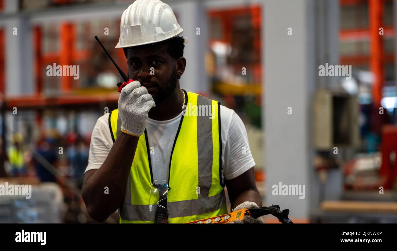 African american Foreman or Worker Control Crane industriali fornitori per il caricamento in fabbrica linea di produzione Foto Stock