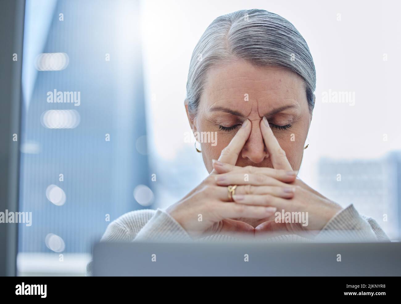 Questo non mi va a modo mio: Una donna d'affari matura seduta da sola in ufficio e sentendosi stressata. Foto Stock