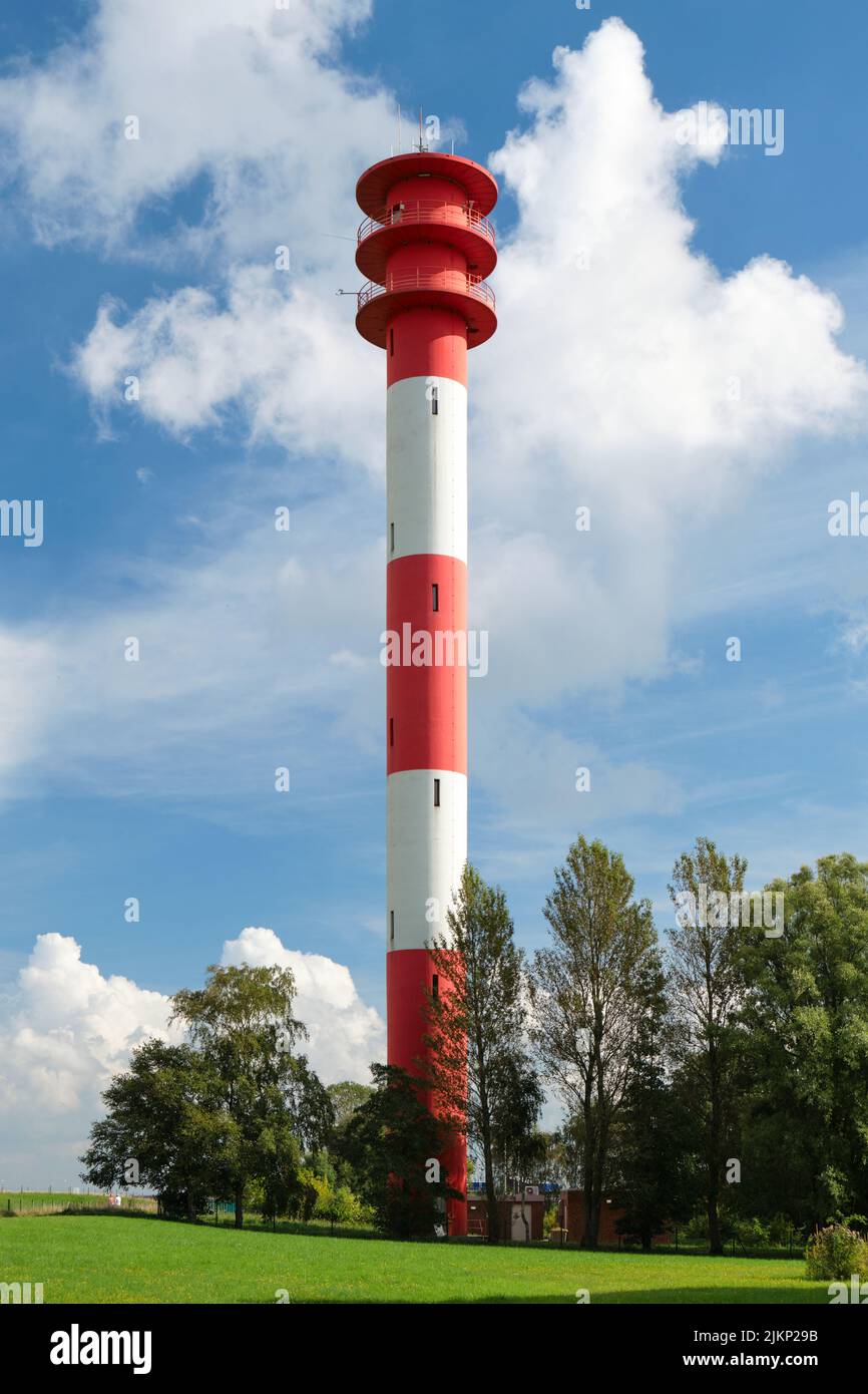 Scatto verticale di un moderno faro rosso e bianco in una giornata di sole nella Frisia orientale presso la costa turistica del Mare del Nord in Germania. Foto Stock