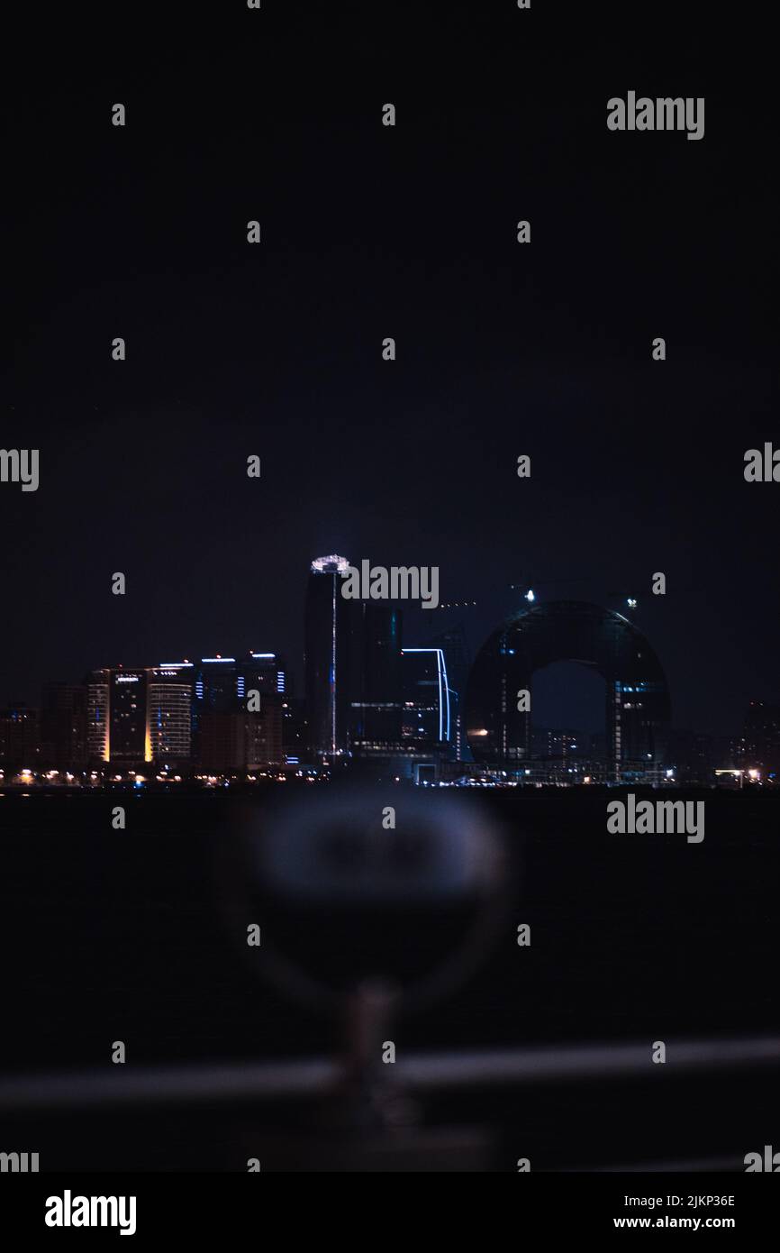 Un bellissimo scatto del paesaggio urbano dal mare contro il cielo notturno con lo spettatore torre nella sfocata zona boschita Baku, Azerbaigian Foto Stock