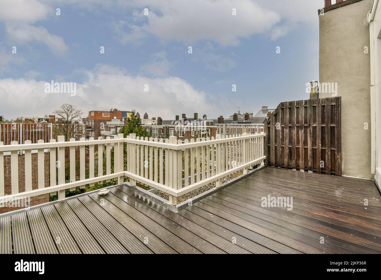Piccolo balcone in mattoni con ringhiere metalliche, sedia e porta in legno Foto Stock