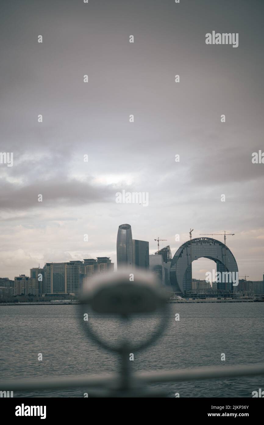 Un bellissimo scatto del paesaggio urbano dal mare contro il cielo nuvoloso con il visore della torre nella falda offuscata Foto Stock