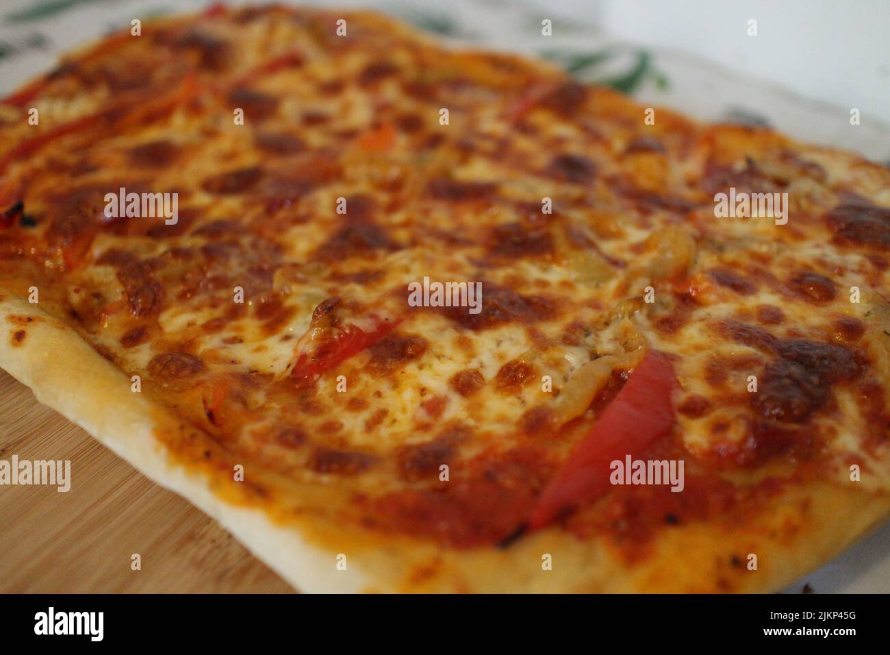 Un primo piano di una fetta di pizza siciliana su una tavola di servizio in legno con sfondo sfocato Foto Stock