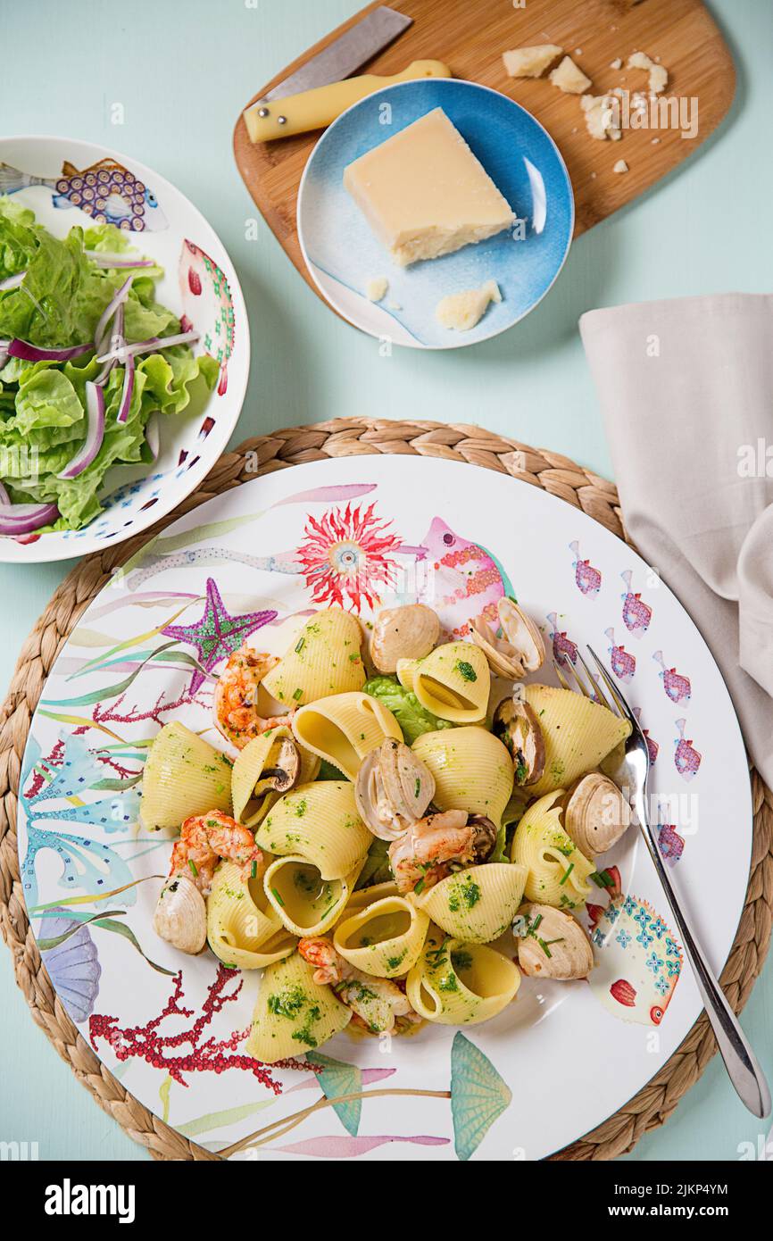 Un colpo verticale di pasta con pesce con insalata e formaggio sul lato Foto Stock