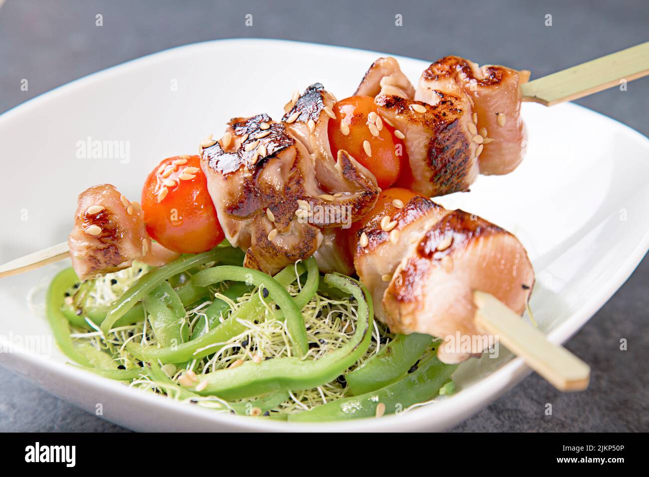 Un primo piano di barbecue su spiedini di legno con verdure in un piatto bianco Foto Stock