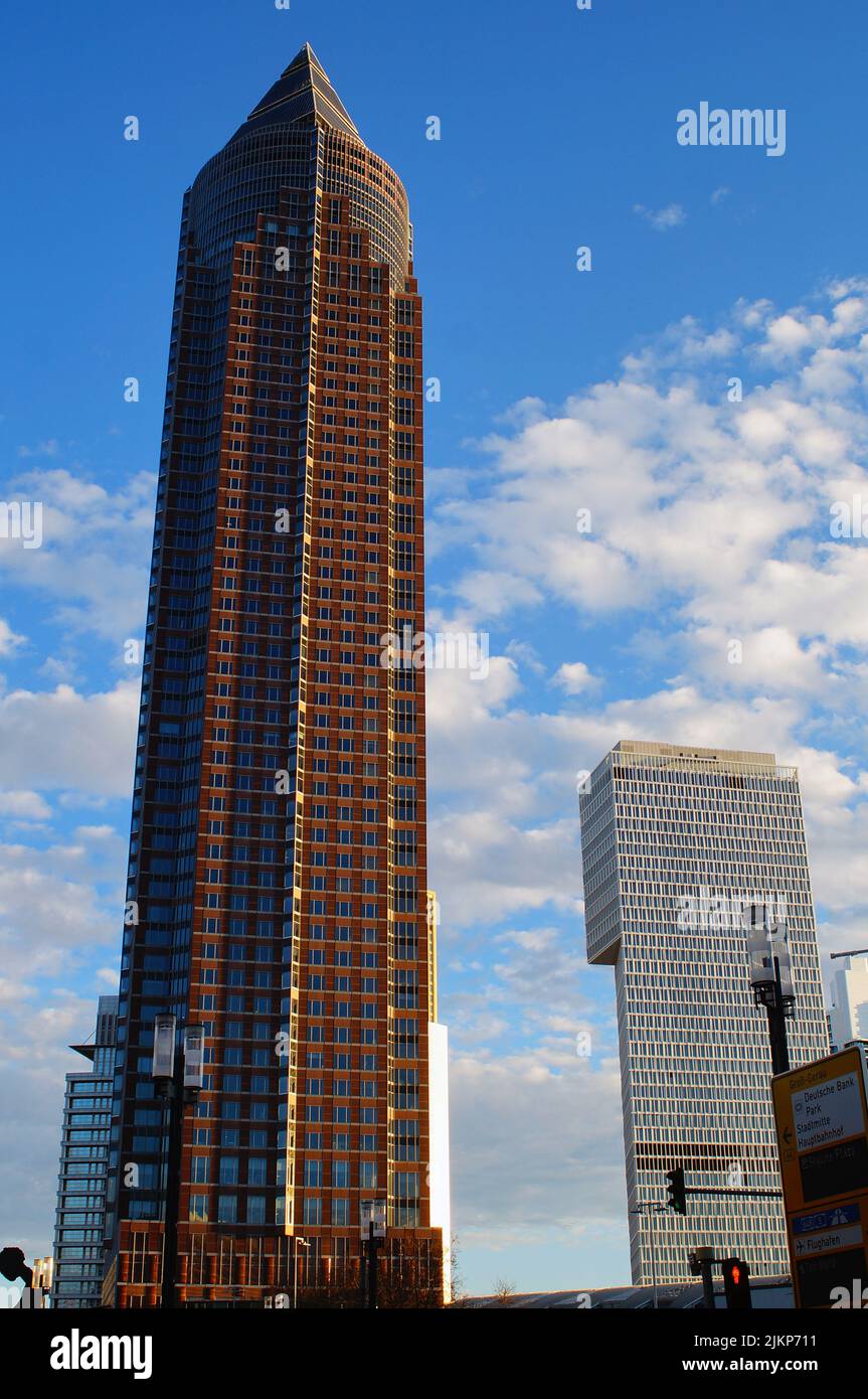 Vista grandangolare del Messeturm e della torre recentemente completata a Messe Frankfurt, Germania. Dicembre 2021. Cielo blu con nuvole. Foto Stock