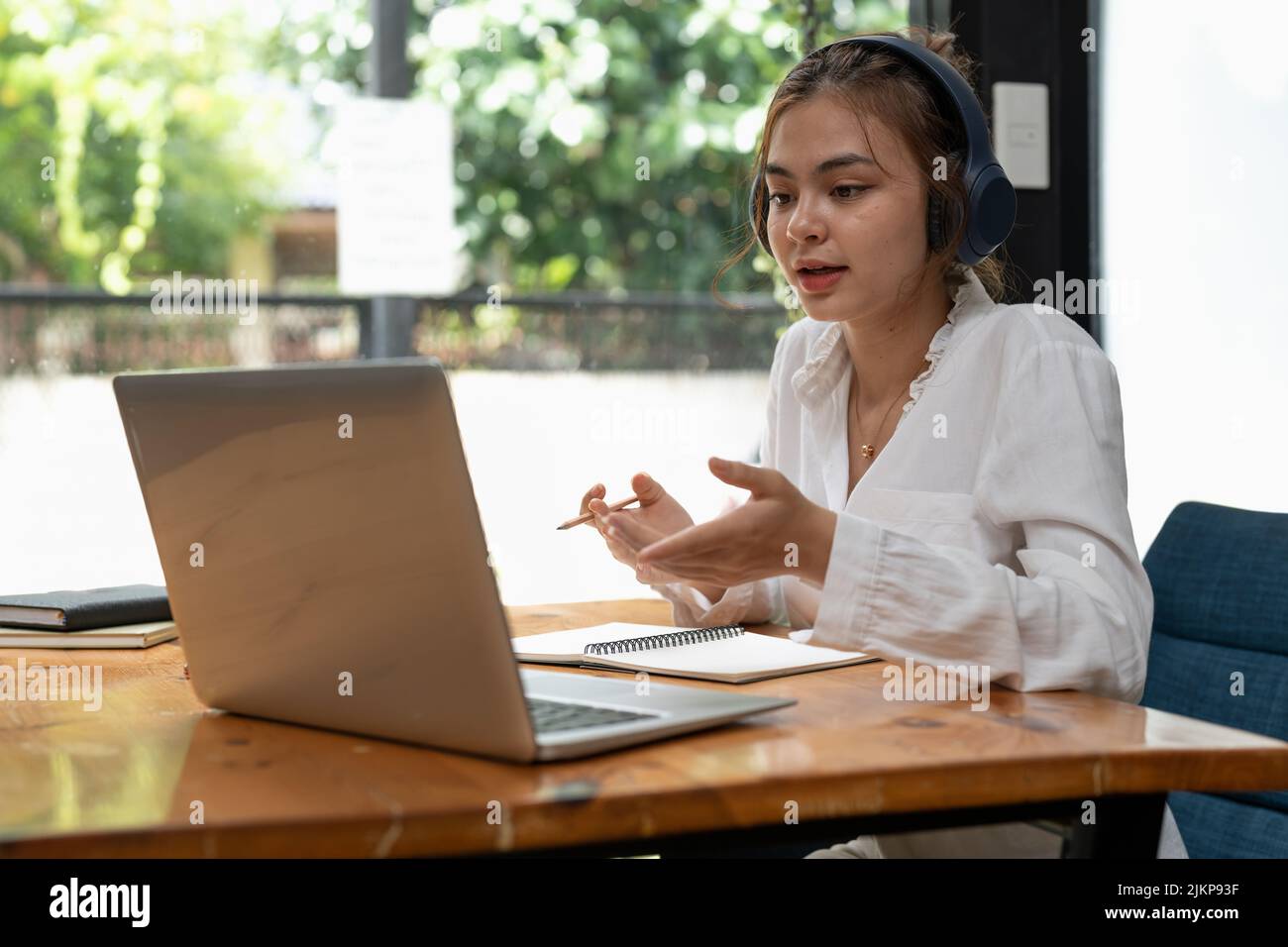 Formazione online, e-learning. Giovane donna che studia da remoto, utilizzando un notebook, ascoltando lezioni online, prendendo appunti mentre si siede a casa. Foto Stock