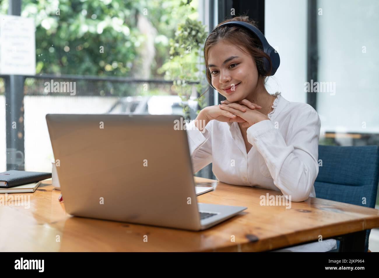 Formazione online, e-learning. Giovane donna che studia in remoto, utilizzando un notebook, ascoltando il webinar online a casa Foto Stock