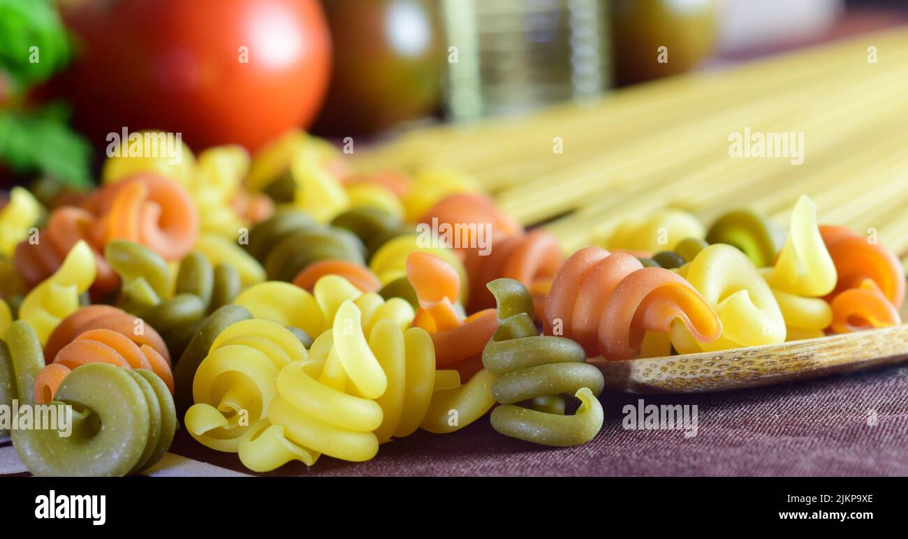 un primo piano di pasta colorata, pomodori e altri ingredienti, che forniscono benessere al nostro corpo. Foto Stock