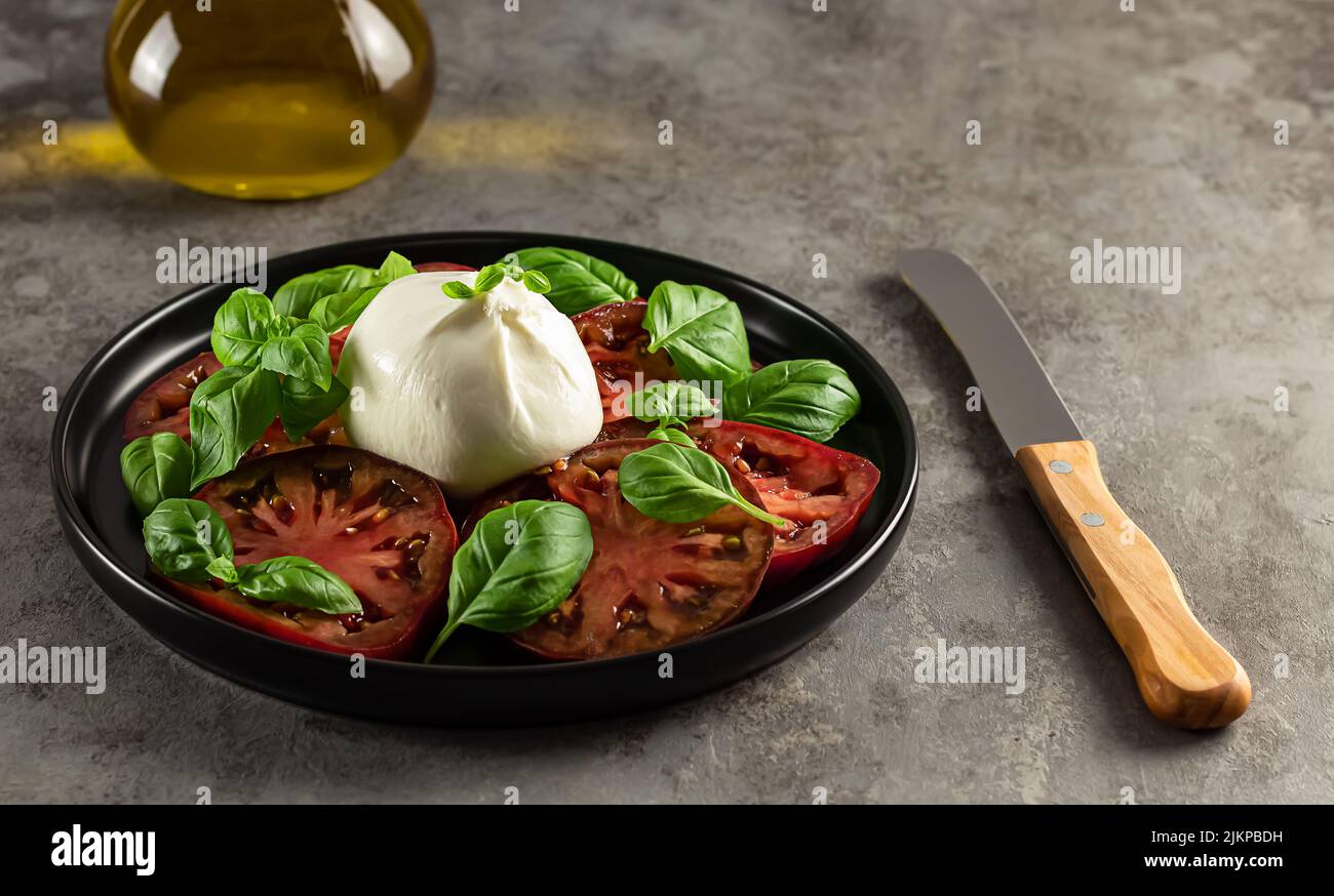 Primo piano di antipasto vegetariano. Pomodori e burrata con basilico fresco. Foto Stock