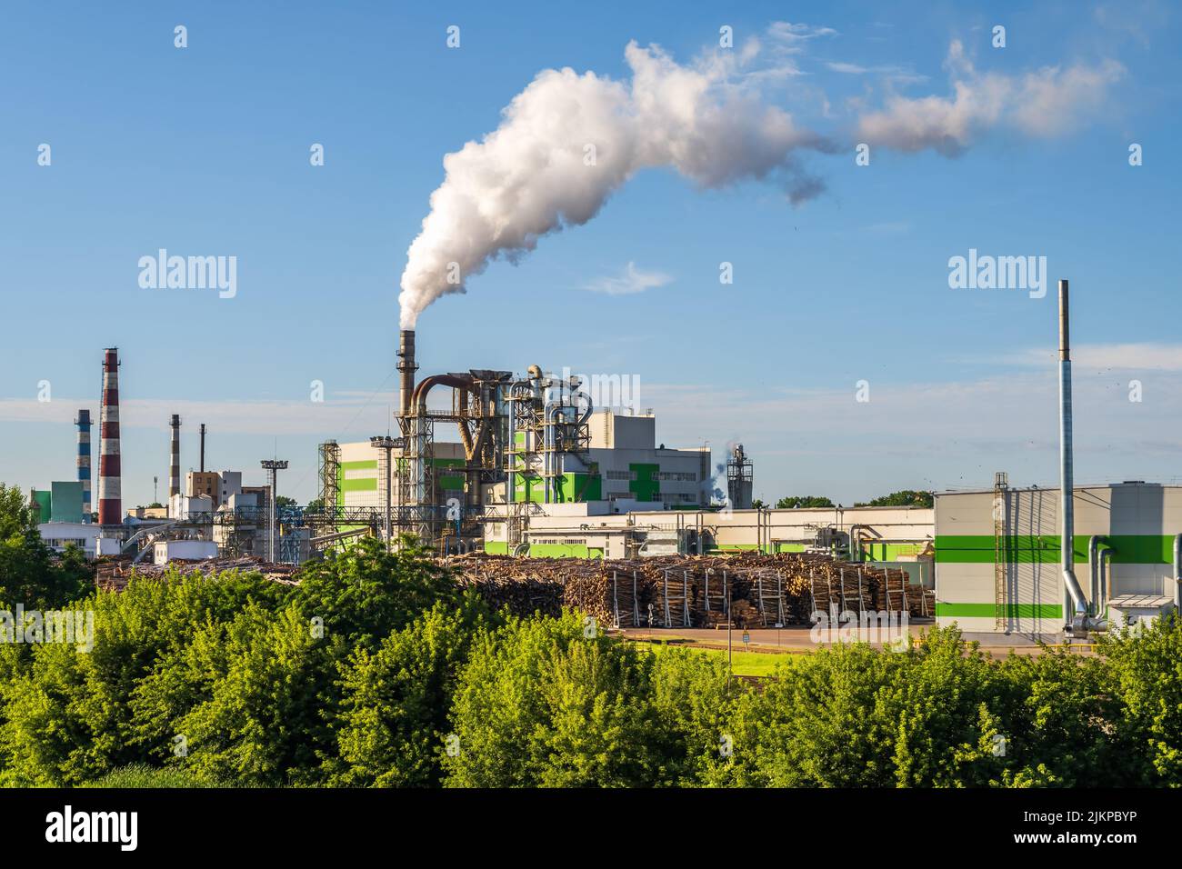 pipe di impresa di lavorazione del legno pianta segheria con bella riflessione in acqua blu del fiume. Concetto di inquinamento atmosferico. Ambienti industriali del paesaggio Foto Stock