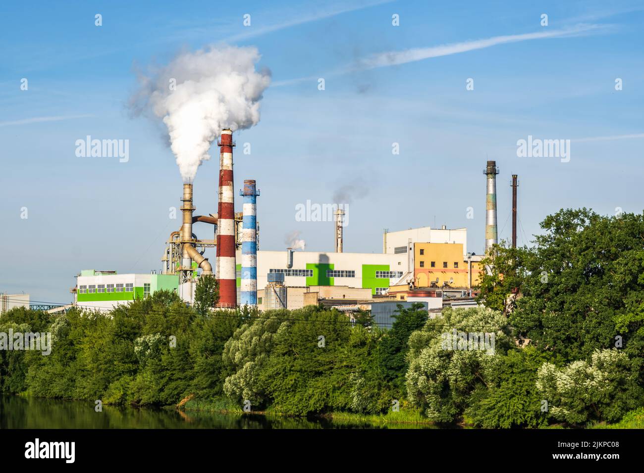 pipe di impresa di lavorazione del legno pianta segheria con bella riflessione in acqua blu del fiume. Concetto di inquinamento atmosferico. Ambienti industriali del paesaggio Foto Stock