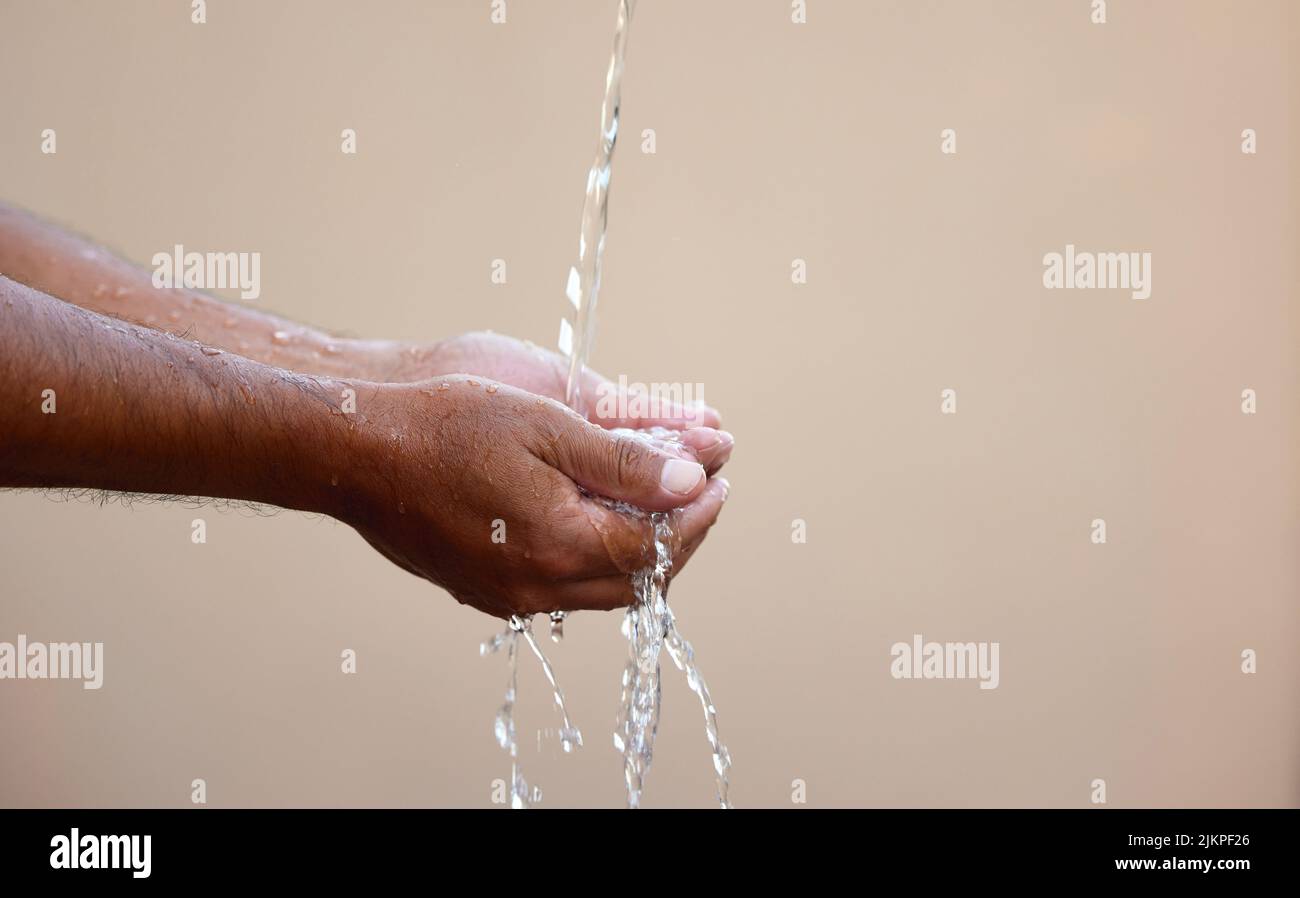 L'acqua è la forza trainante della natura, della vita, dell'esistenza. Un maschio irriconoscibile che lava le mani sotto un flusso d'acqua all'esterno. Foto Stock