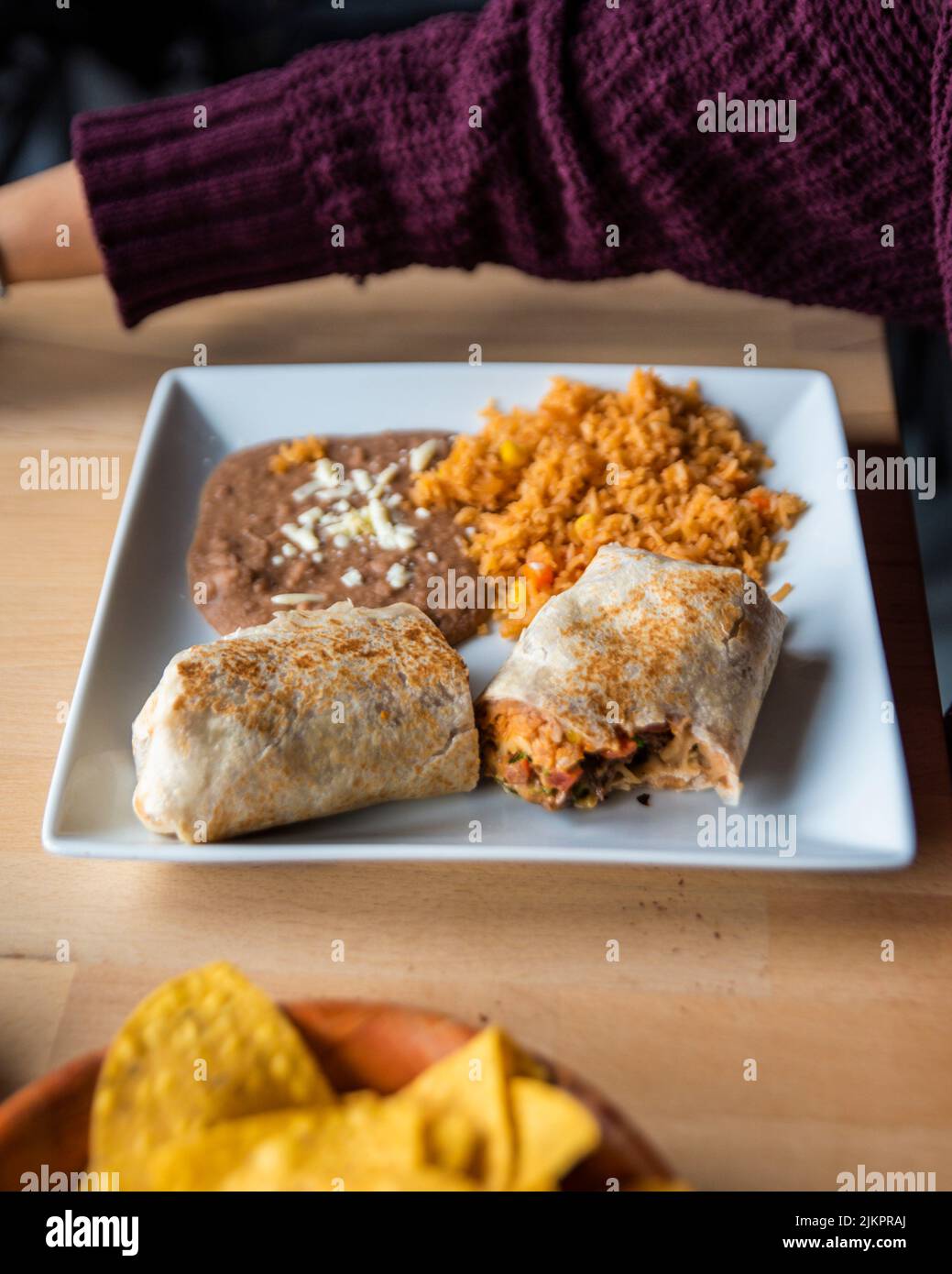 Un primo piano verticale di un piatto con un Burrito messicano con riso e fagioli e salsa sul lato Foto Stock