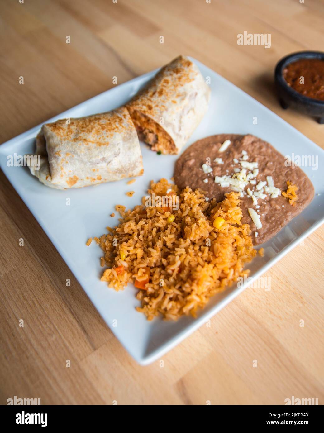 Un primo piano verticale di un piatto con un Burrito messicano con riso e fagioli e salsa sul lato Foto Stock