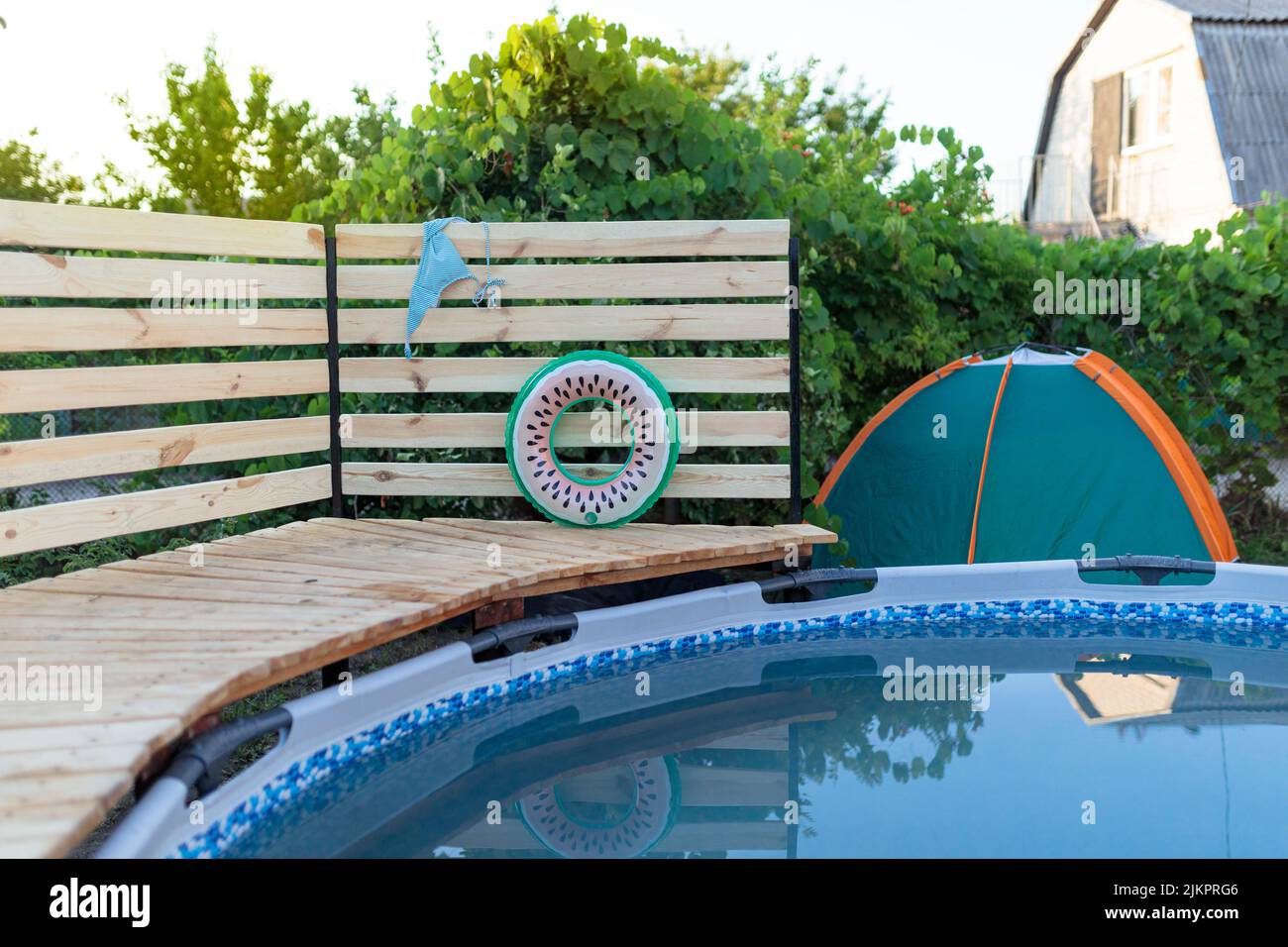 Piscina con struttura grigia sul prato verde con sfondo alberato Foto Stock