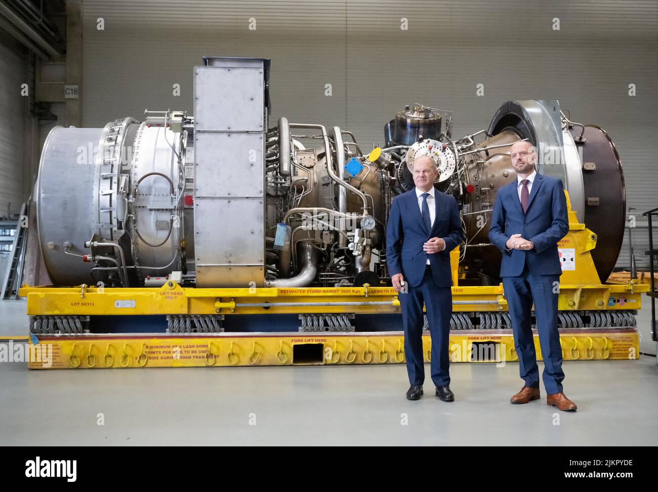 03 agosto 2022, Renania Settentrionale-Vestfalia, Mülheim an der Ruhr: Il cancelliere tedesco OLAF Scholz (SPD) è in piedi con Christian Bruch (r), CEO di Siemens Energy, presso la turbina servita in Canada per il gasdotto Nordstream 1. E' pronta per il trasporto in Russia. Foto: Bernd Thissen/dpa Foto Stock