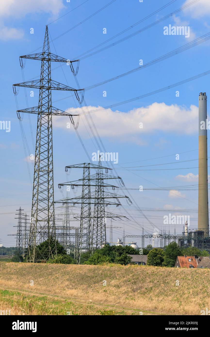 Torri di trasmissione dell'elettricità, piloni o montanti con linee elettriche aeree, vicino alla centrale di generazione dell'energia, Essen, Germania Foto Stock