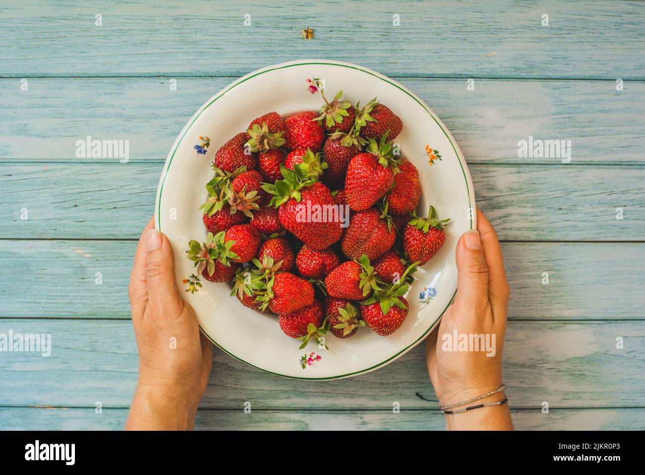 Strawberry background.Woman mani che tengono fresco fragola su plate.Fresh raccolto fragole, top view.mature organico dolce fragola.Summer Foto Stock