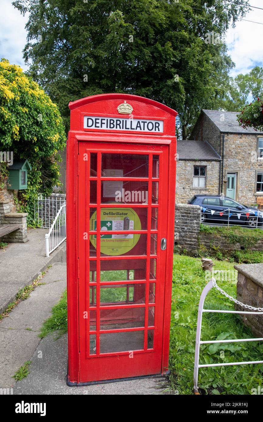 Red London telefono box nel villaggio Lancashire di Waddington essendo usato per ospitare un defibrillatore, Inghilterra, Regno Unito Foto Stock