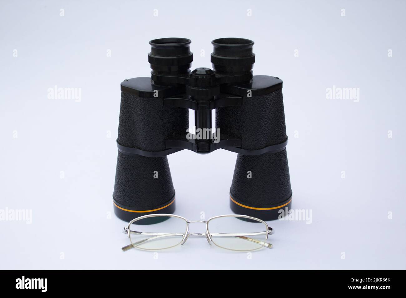 Immagine di un paio di occhiali e binocoli con sfondo bianco Foto Stock