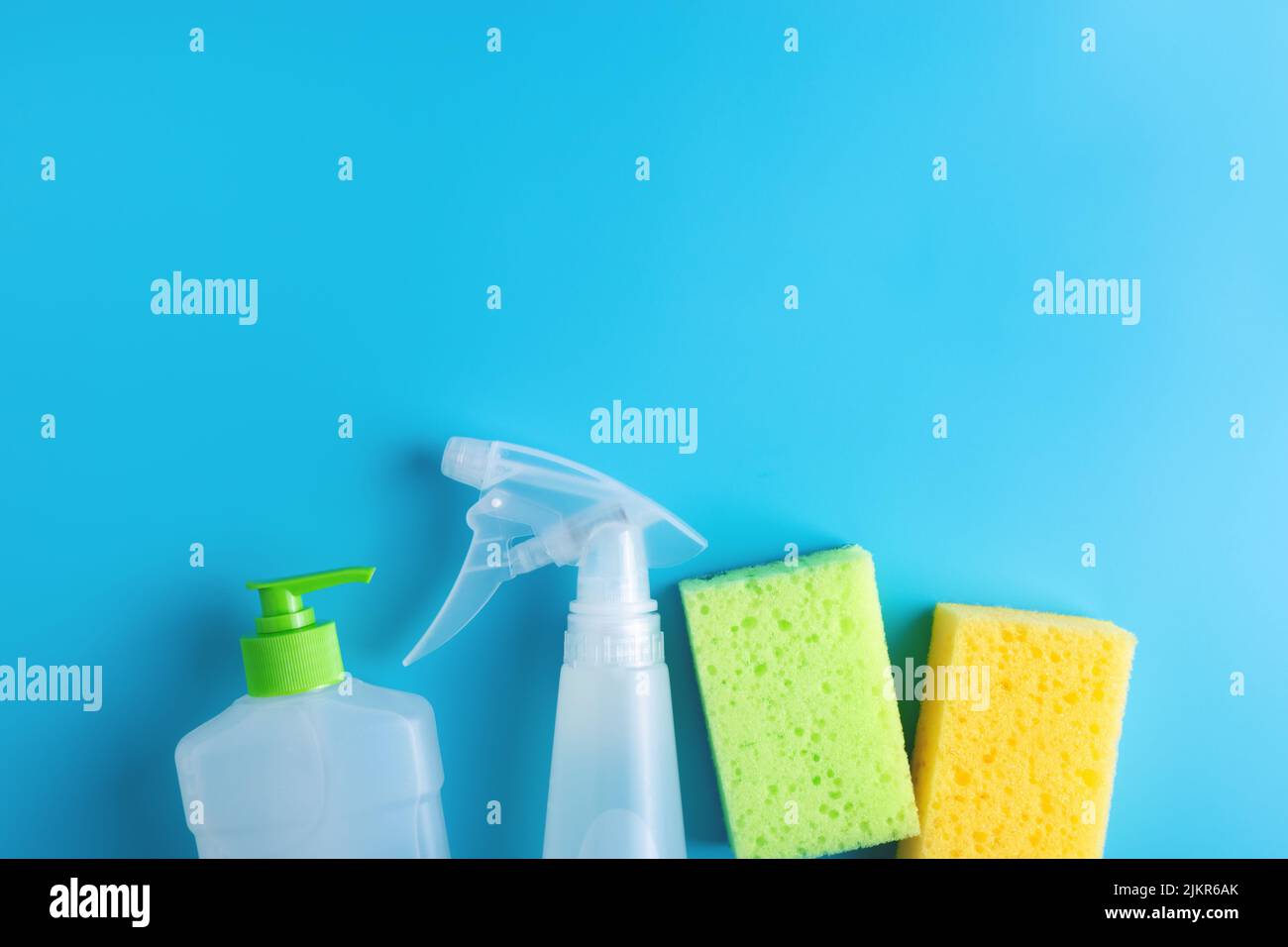Spray detergente, detersivo per piatti, due spugne su fondo blu. Disposizione piatta. Foto Stock